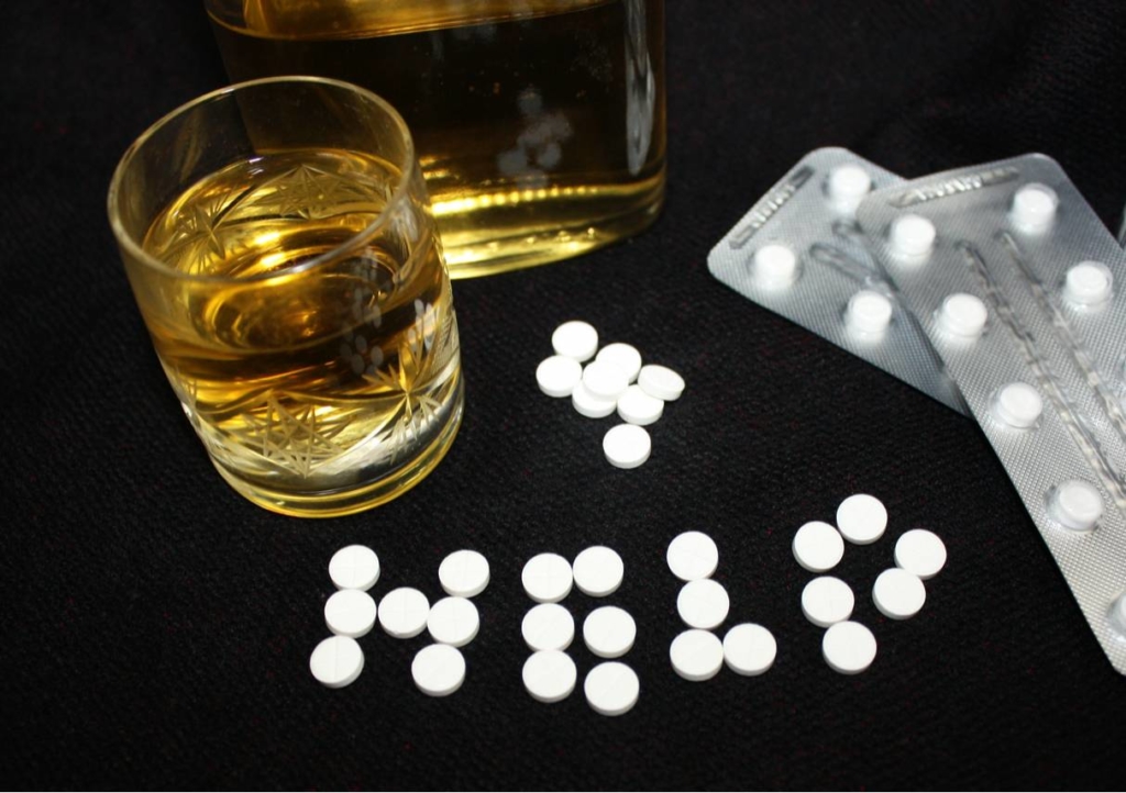 Alcohol sits next to Benzo pills with Help spelled out